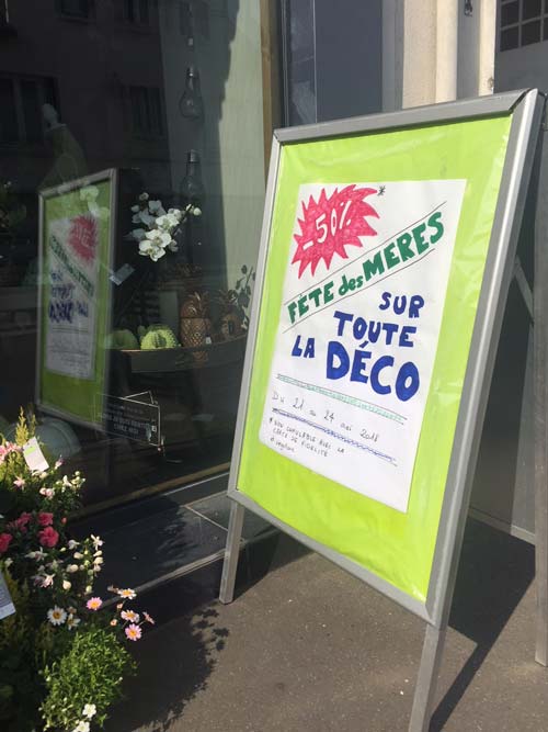 Affiche manuscrite devant la boutique pour annoncer -50% sur toute la déco avant la fête des mères Affiche manuscrite devant la boutique pour annoncer -50% sur toute la déco avant la fête des mères