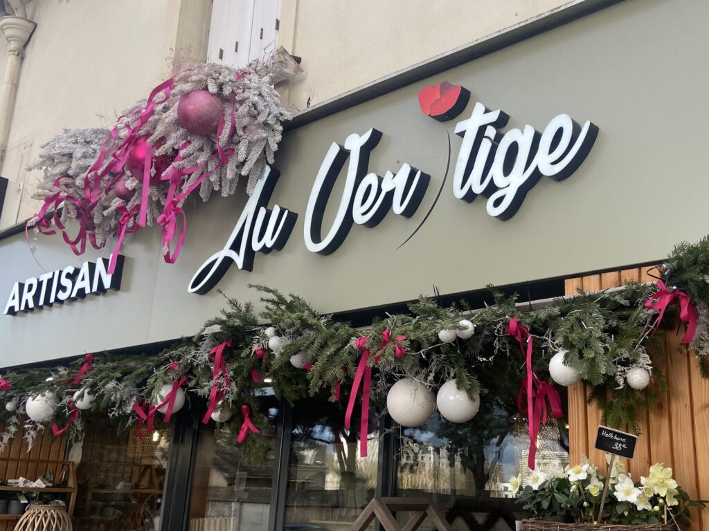 Logo de la devanture de la boutique fleuriste Au Vertige avec décos de Noël